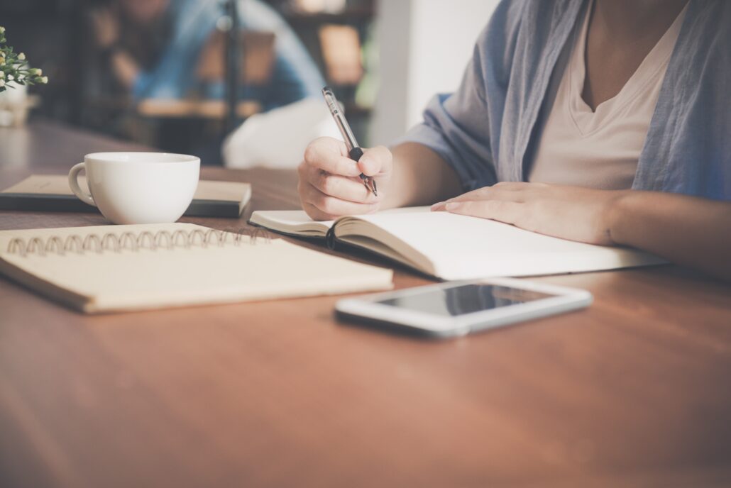 A woman sitting with a note book and calculator writing a budget