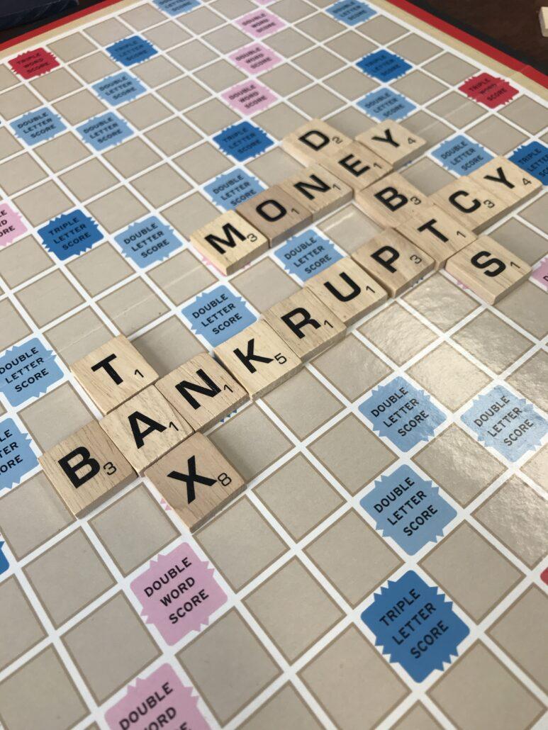 Scrabble Board with debt and finance words on it.