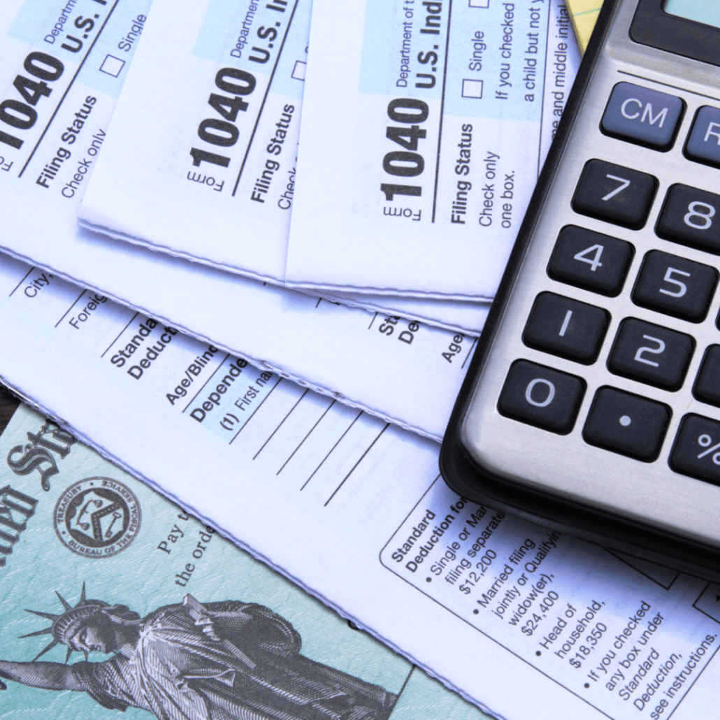A pile of documents, including tax returns and a tax refund check plus a calculator.